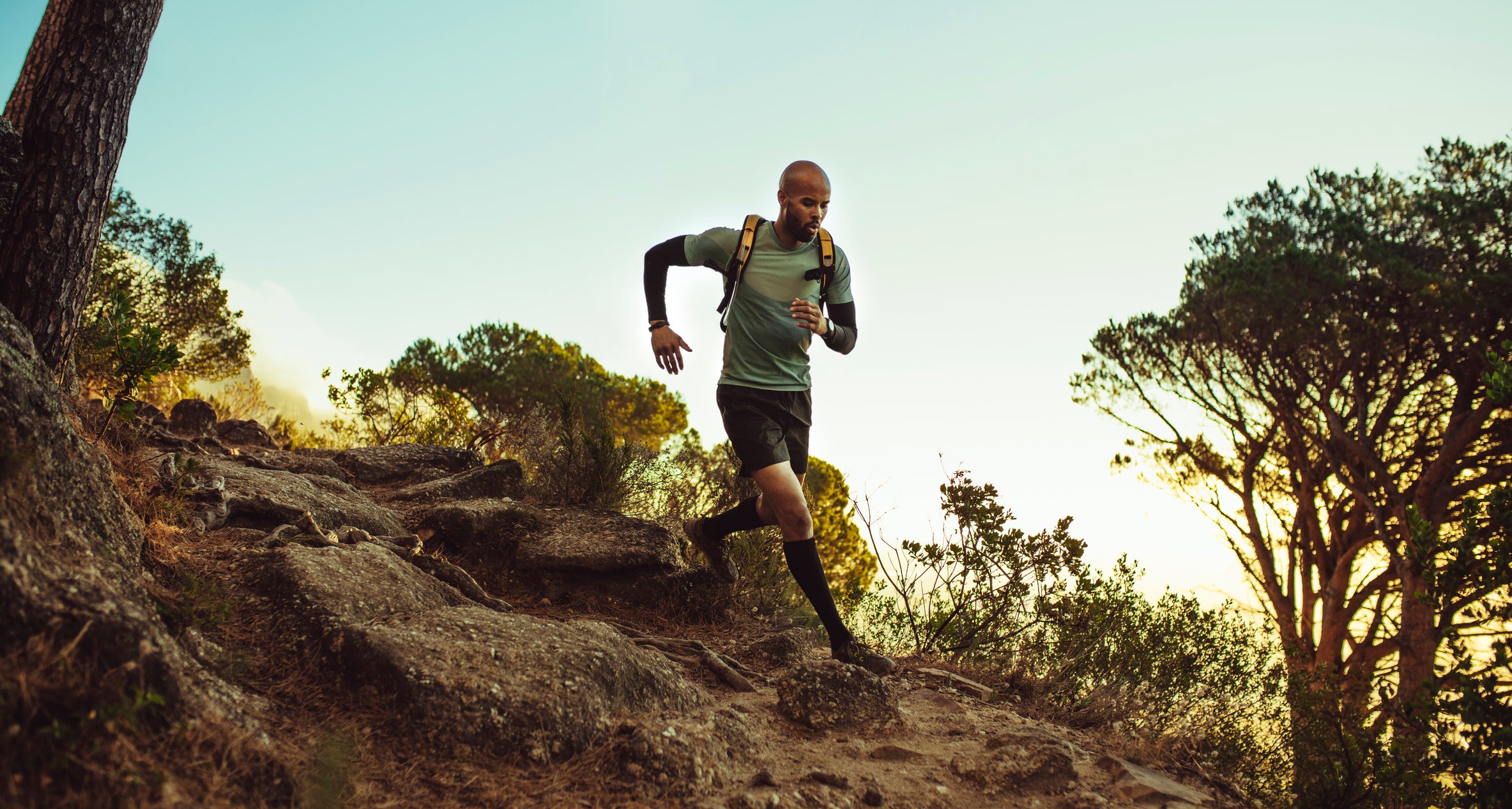 Man running on mountain trail. Fitness male running through rocky mountain path.