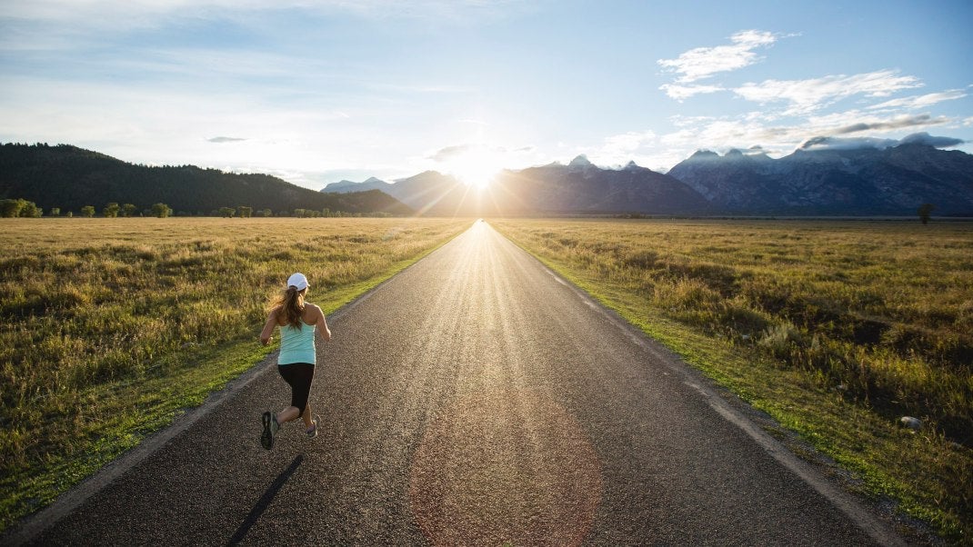 A woman running near the Teton mountains in Jackson Hole, Wyoming.