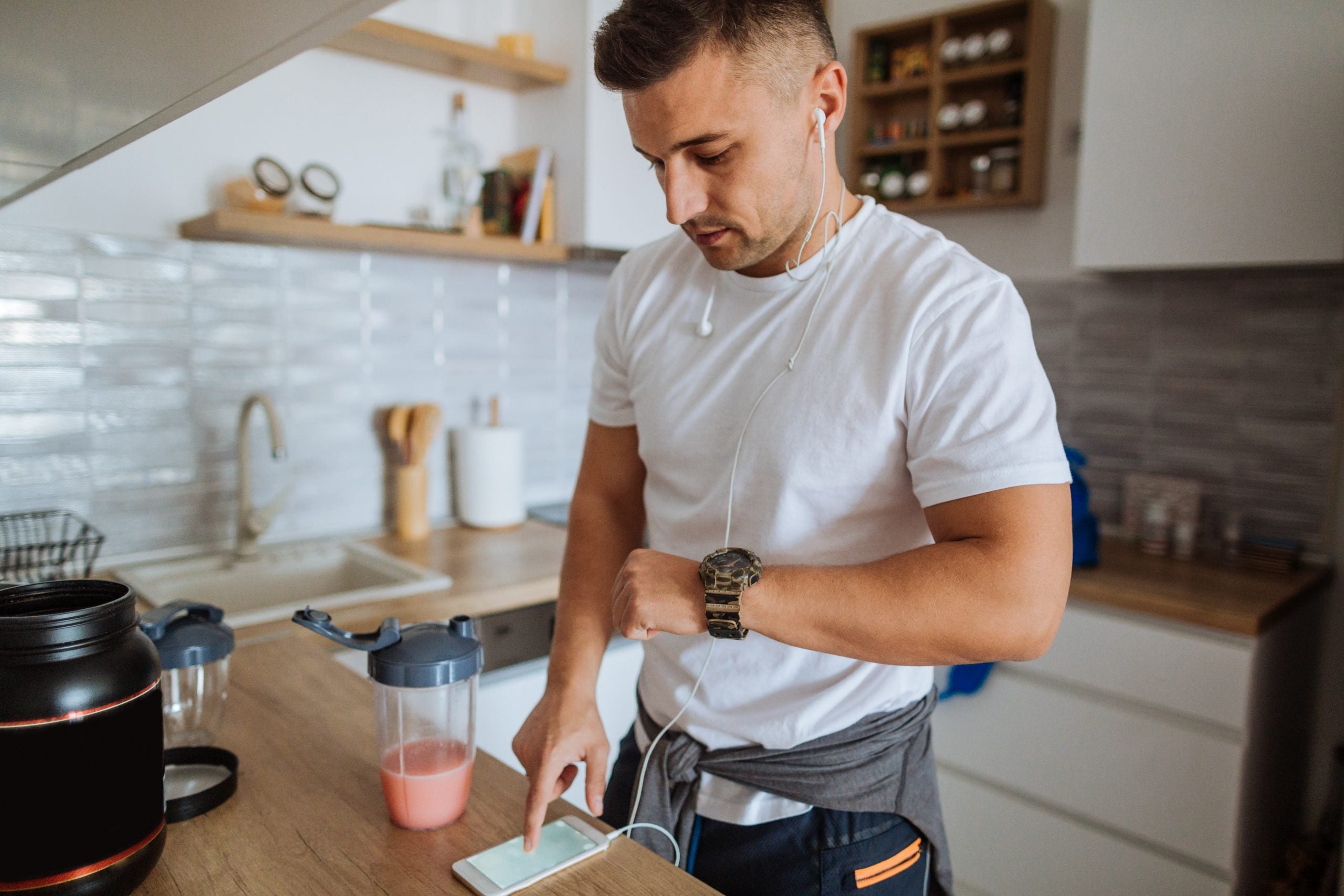 Young man synching smartphone app with smart wear device before exercising