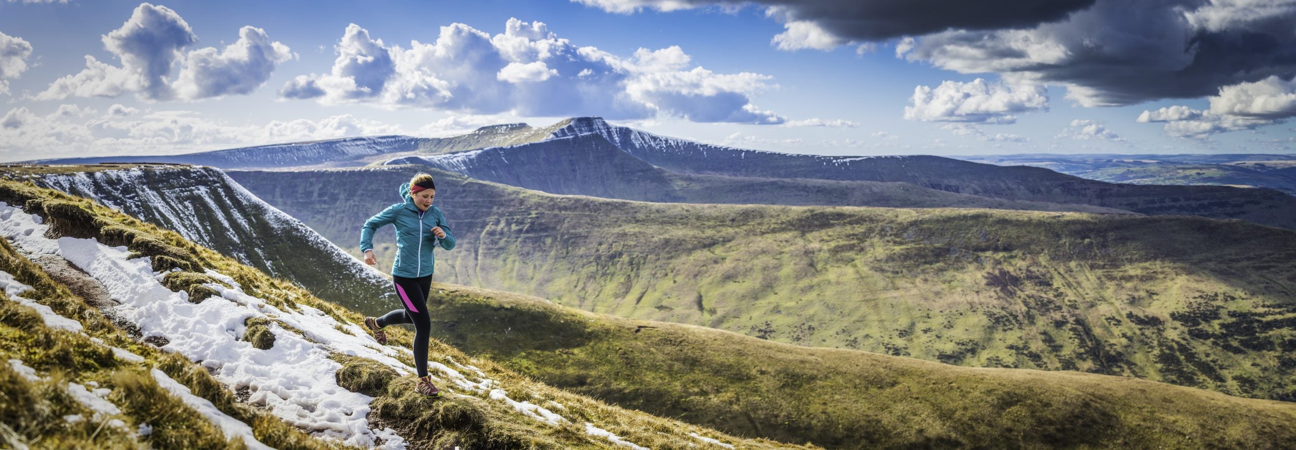 Active teenager trail running along rocky path high in the picturesque mountain wilderness of the Brecon Beacons National Park, Wales. ProPhoto RGB profile for maximum color fidelity and gamut.