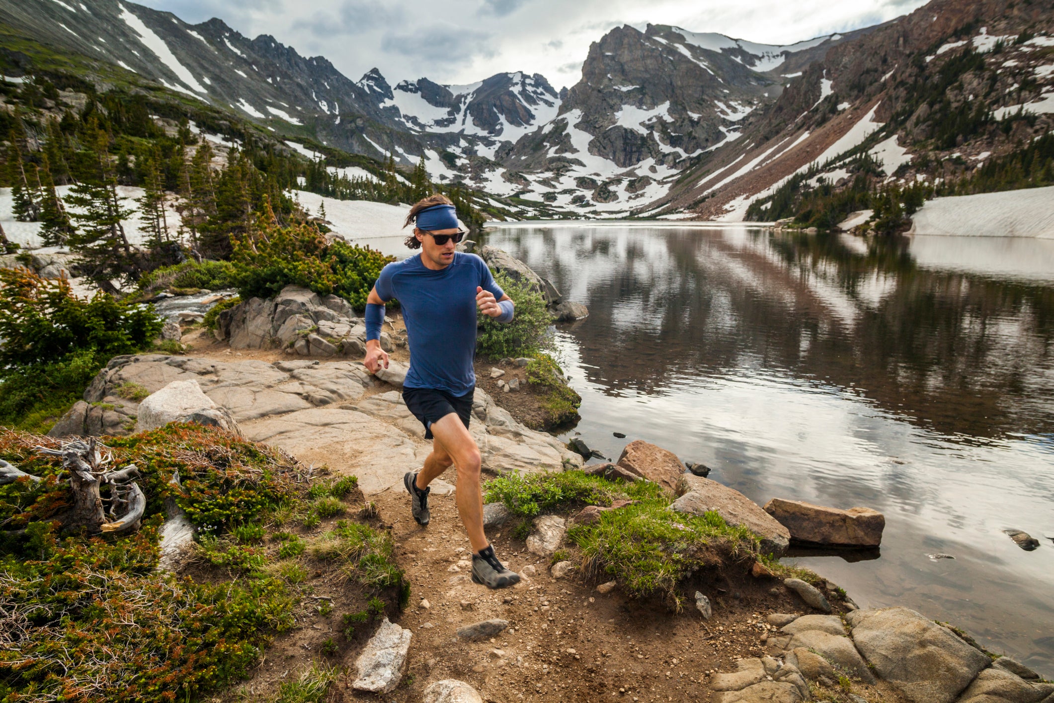 A man runs along the shore of Lake Isabelle in Indian Peaks Wilderness, Colorado. Navajo (l-r), Apache, and Shoshoni Peaks are visible in the background. (A man runs along the shore of Lake Isabelle in Indian Peaks Wilderness, Colorado. Navajo (l-r),