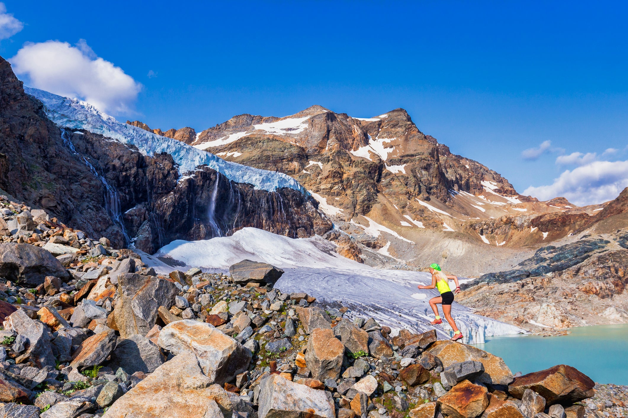 Young trail runner run on rocks with view on the glacier.  Valmalenco, Valtellina, Lombardia, Italy, Europe.