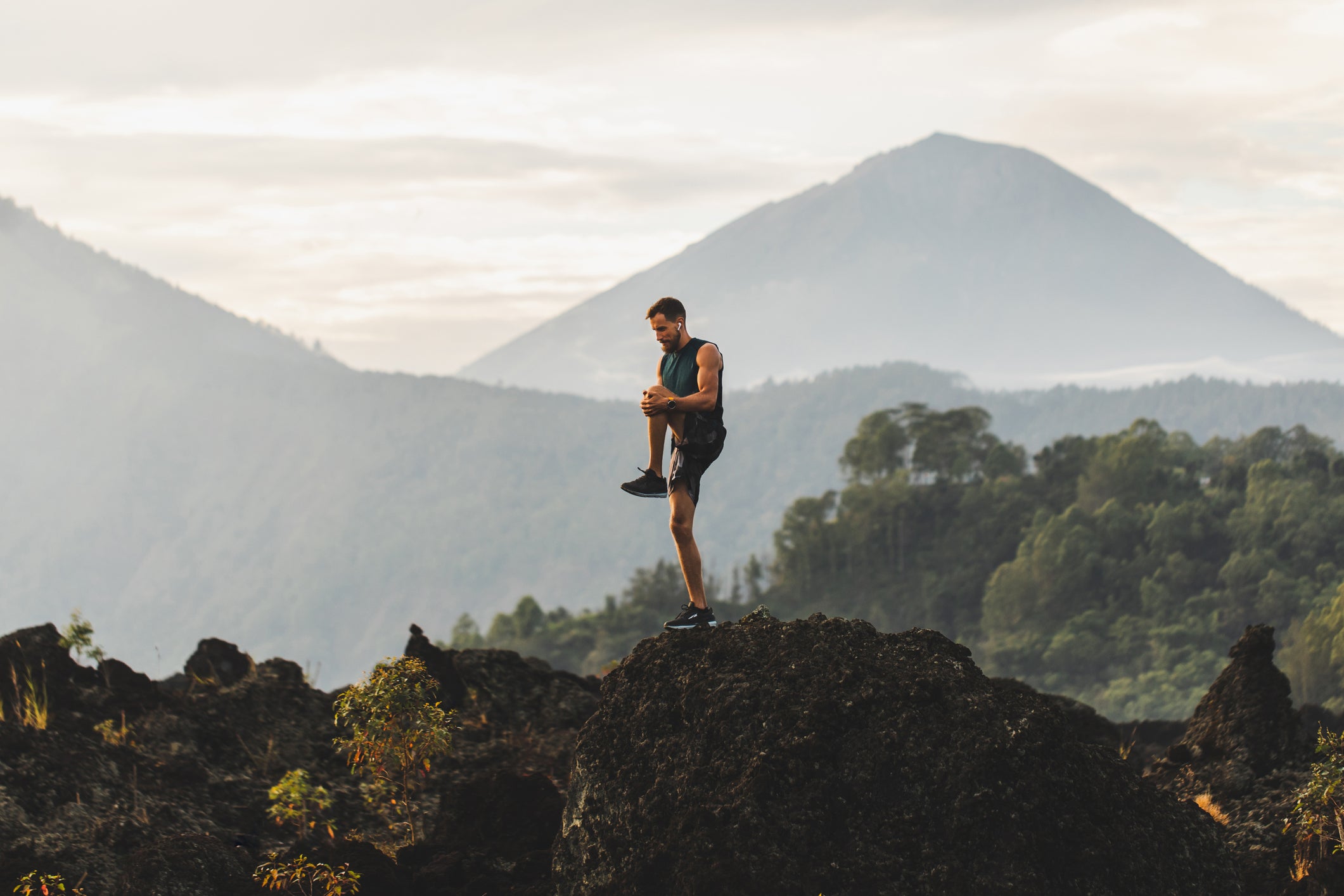 Man doing stretching and preparing for workout and running outdoors. Amazing mountain view on background. Adventure sports concept.