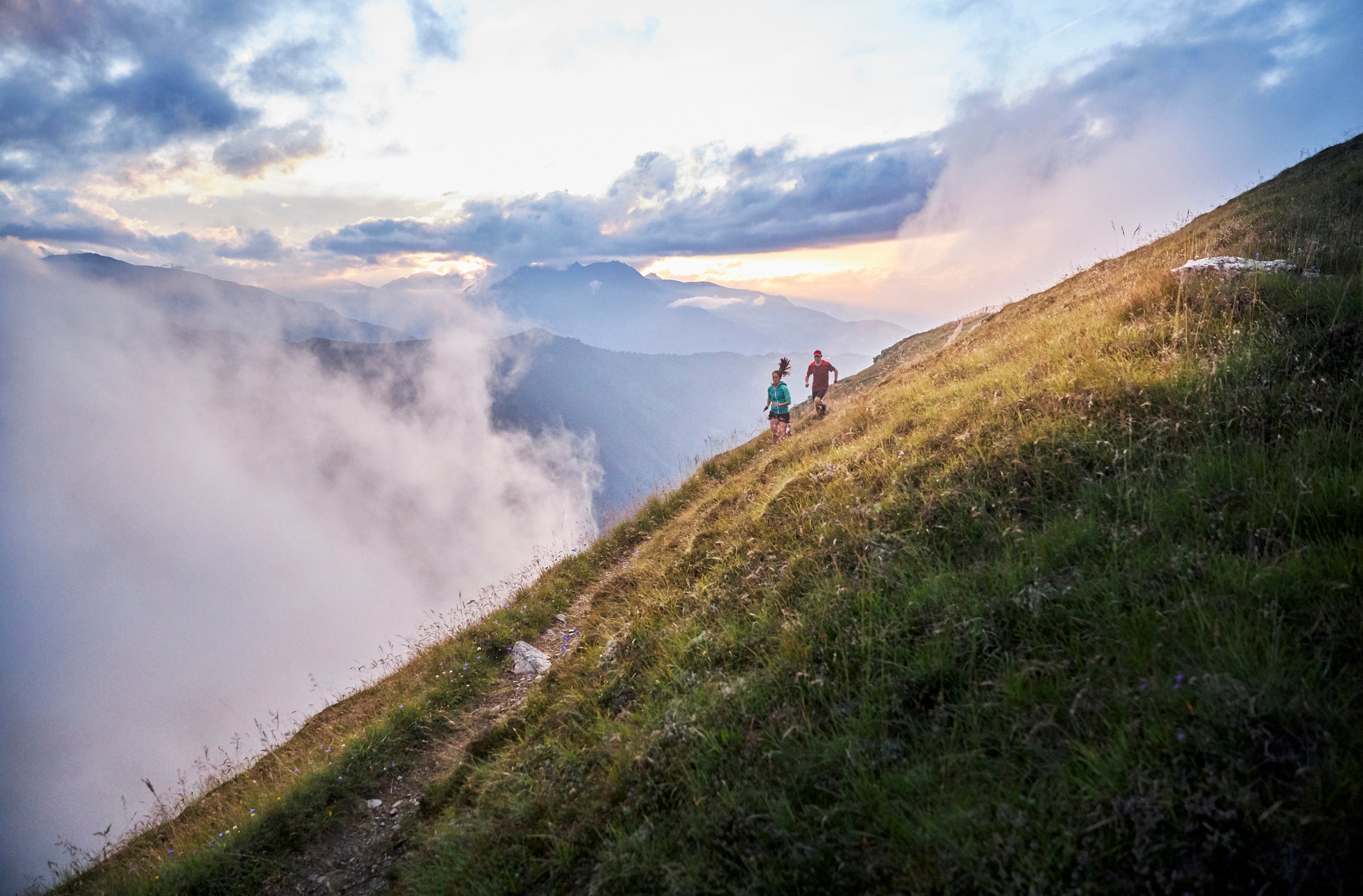 Man and woman running uphill in the mountains