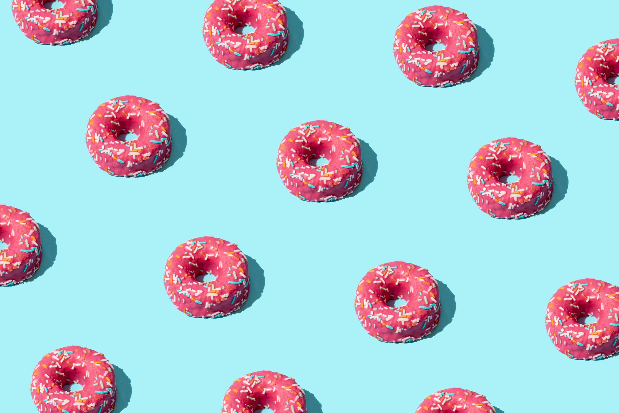 High Angle View Of Many Pink Donuts On Turquoise Colored Background