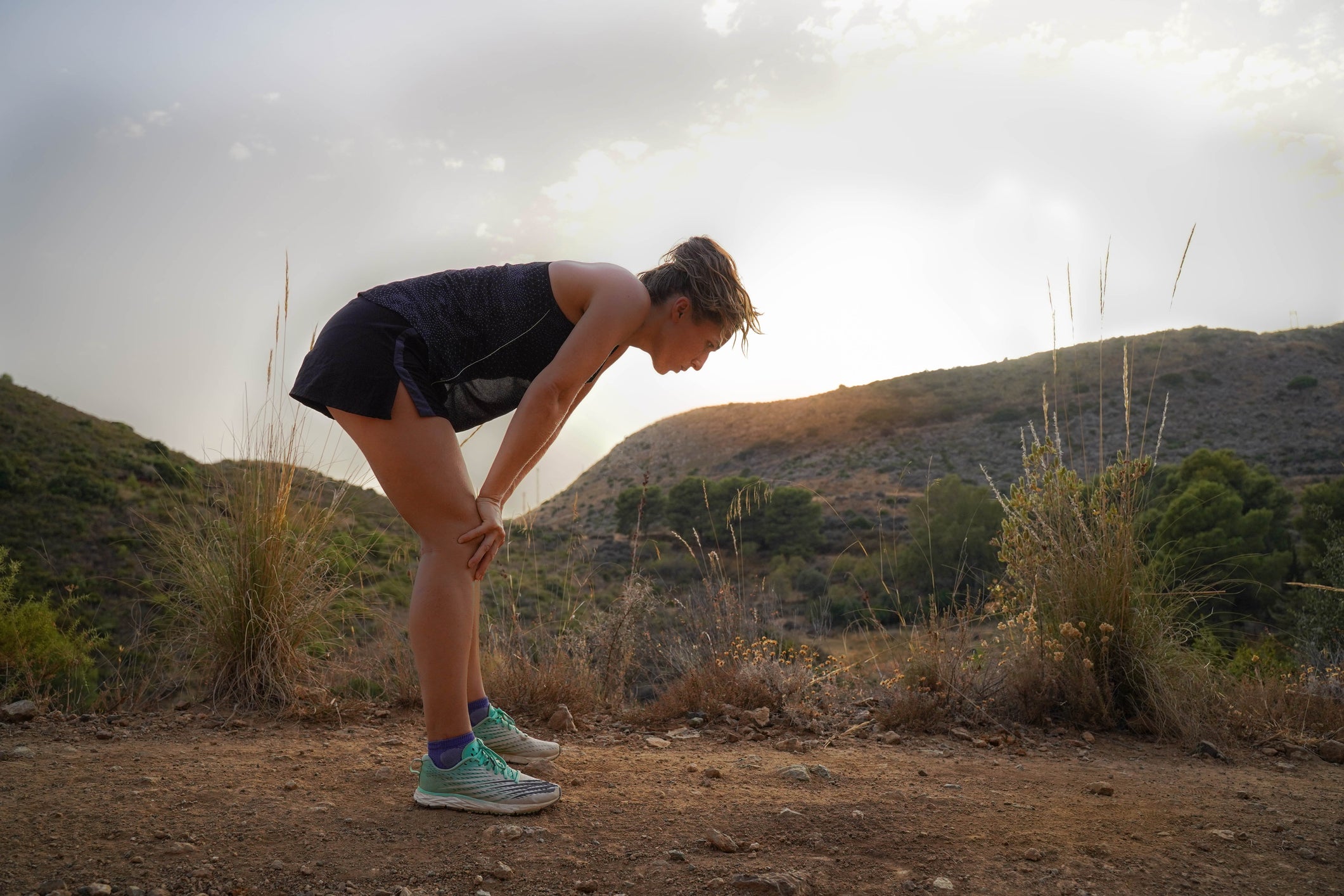 White woman practicing trail running and looking at the interval times on her watch with gps.