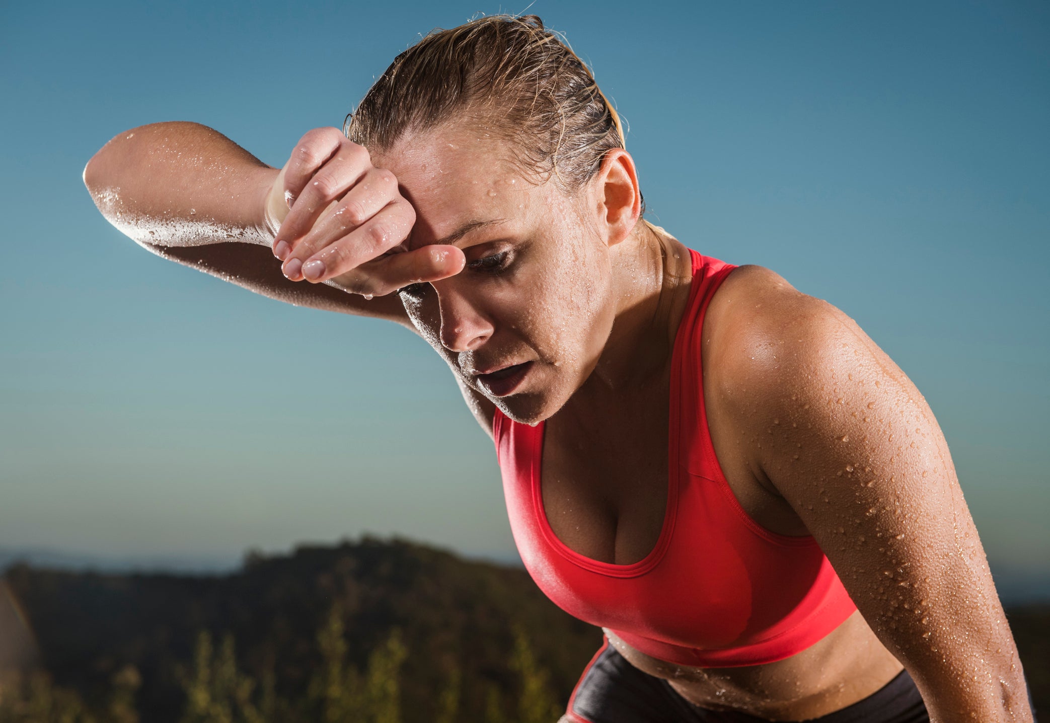 Caucasian woman wiping sweat from forehead