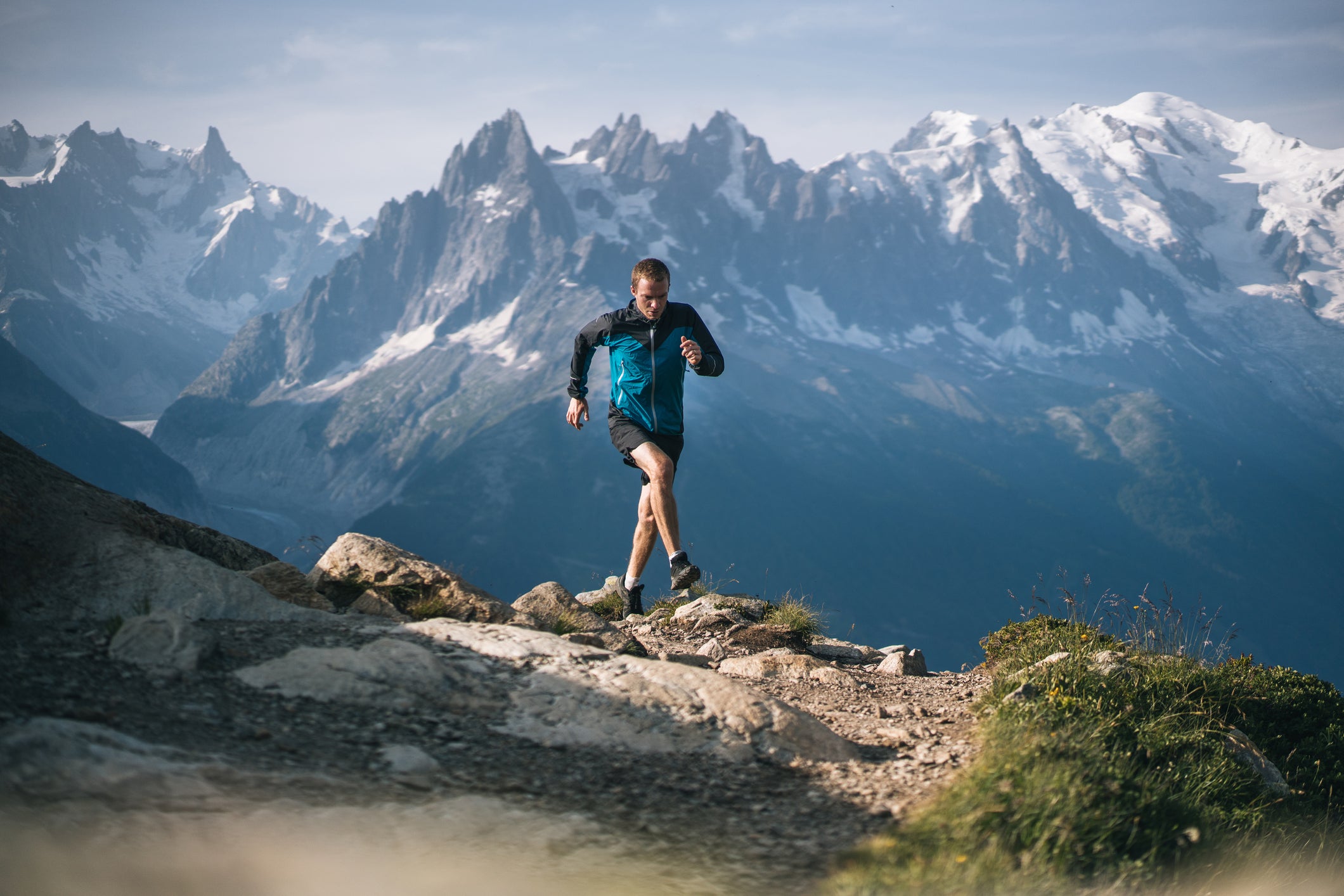 He is on a high mountain path with dramatic sky and clouds behind