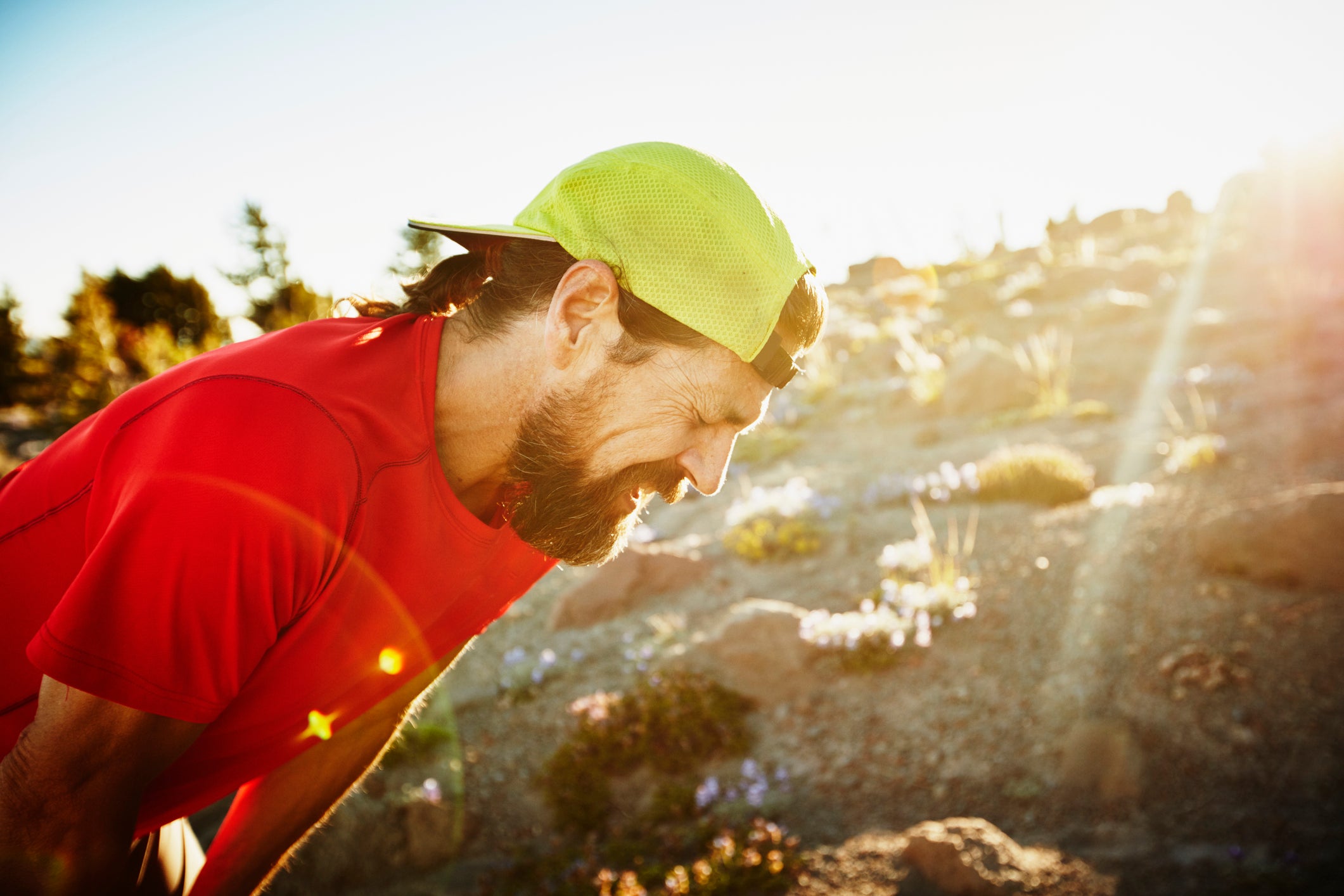 Mature male trail runner breathing hard after run on mountain