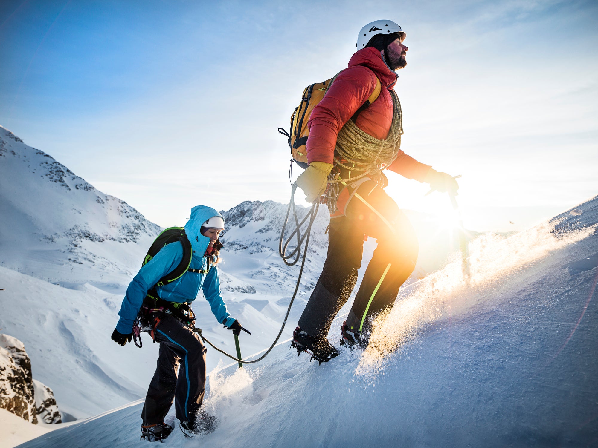 Mountain climber leading up a snowy ridge at sunrise.