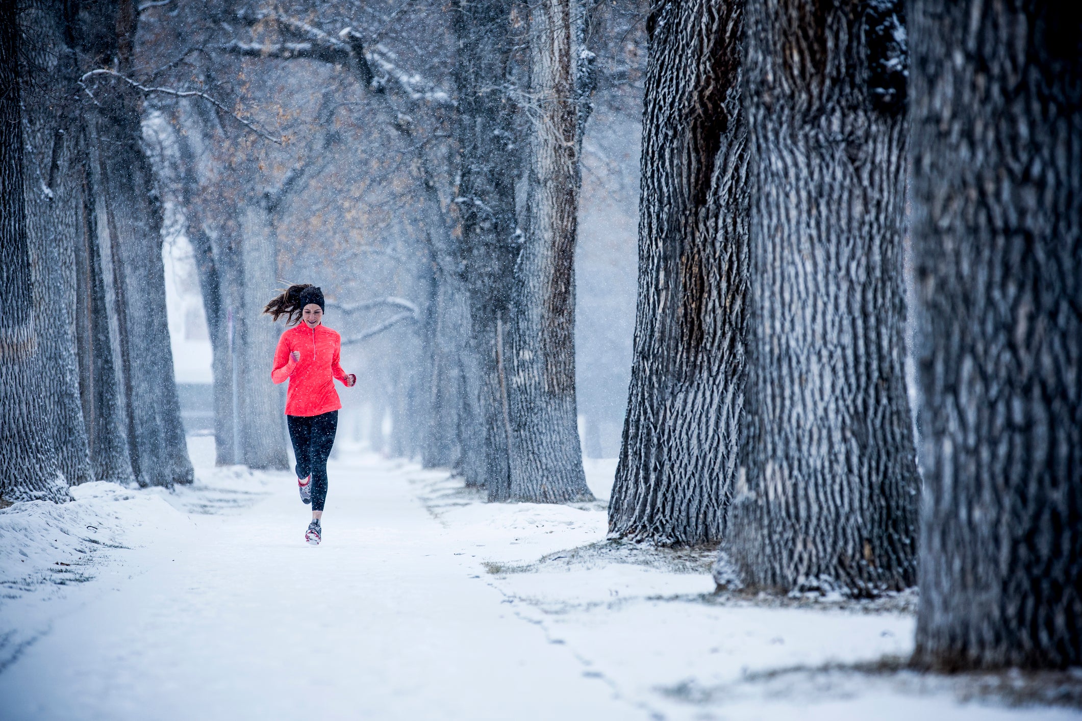 A woman jogging a snowy path in the Winter.