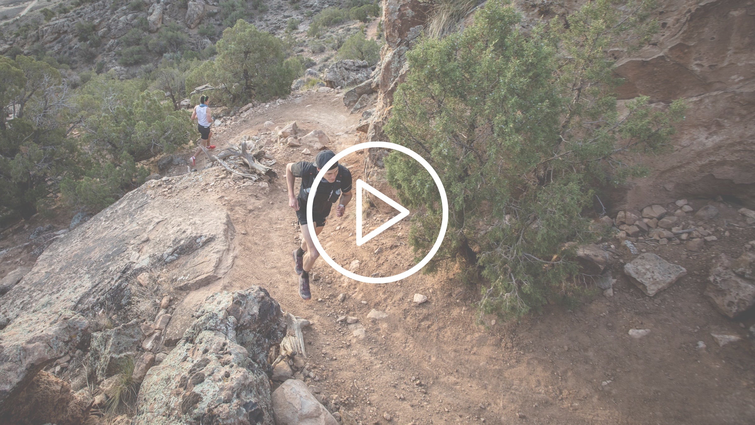 two men run up a desert trail switchback