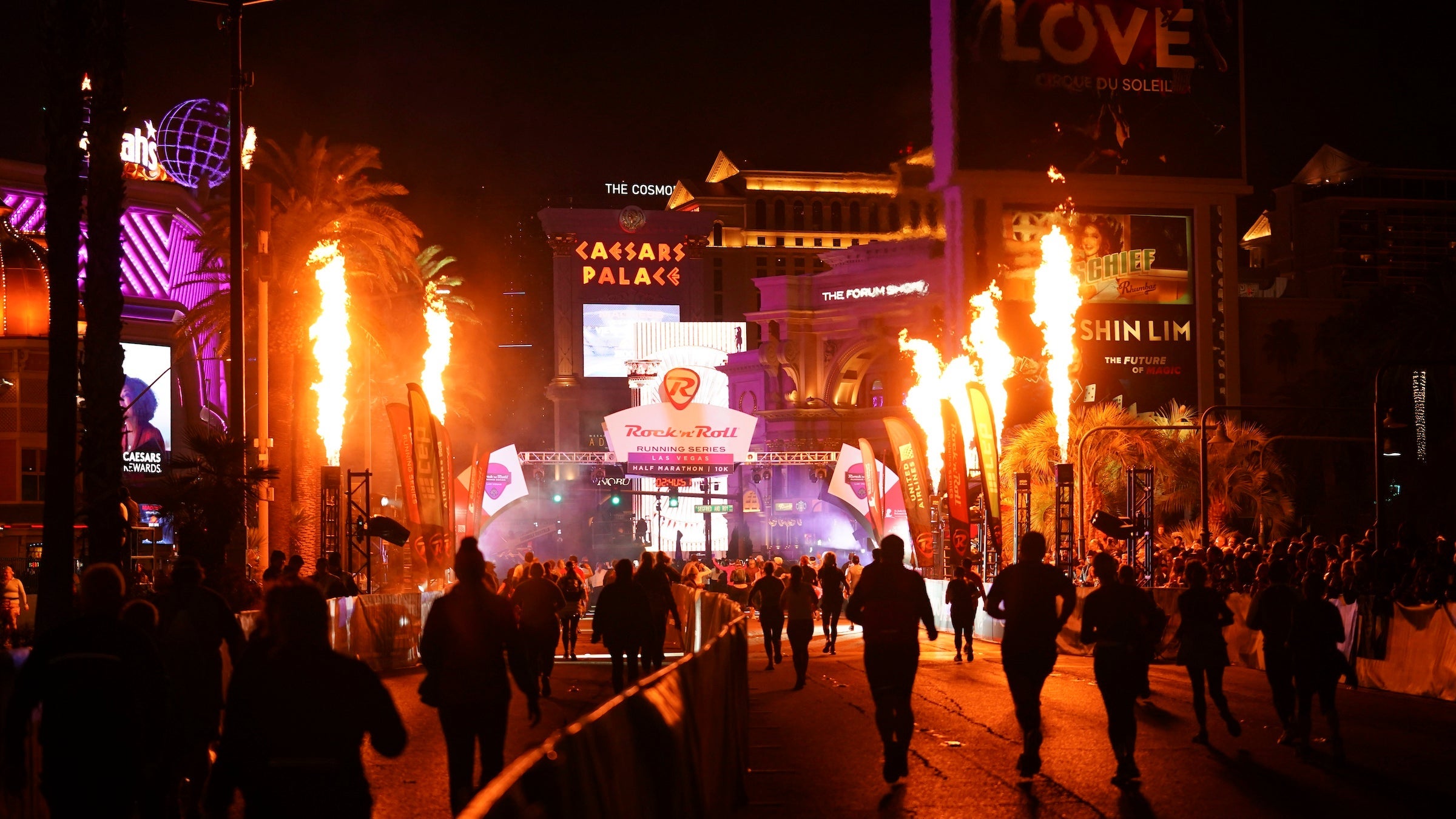 runners finish on the Las Vegas Strip at night, with flames and lights